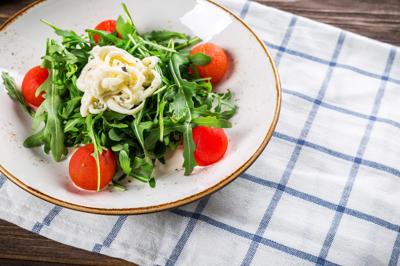Ensalada de rúgula con duraznos acaramelados, stracciatella de búfala y reducción de balsámico